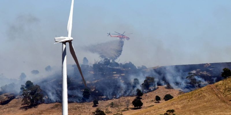 Aerial view of fire bombing plane flying near wind turbines