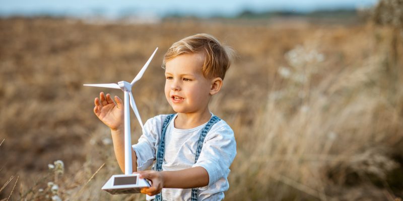 Boy playing with toy wind turbine outdoors